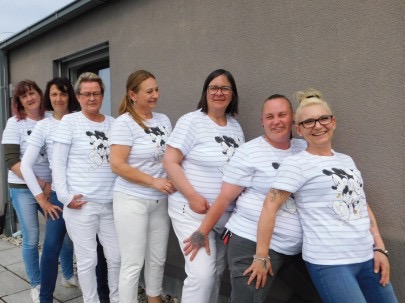 Das Team des Pflegedienstes Sonne, locker aufgereiht an einer Hauswand